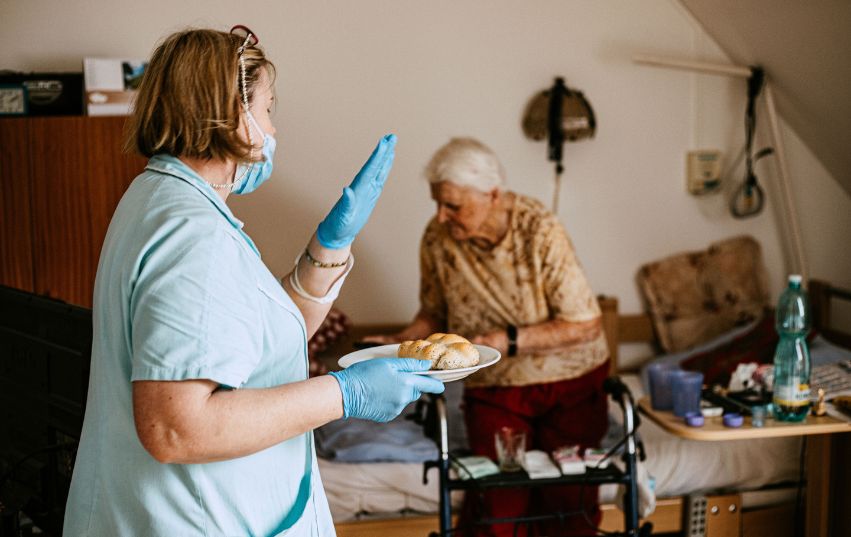 Pečovatelka nese svačinu seniorce